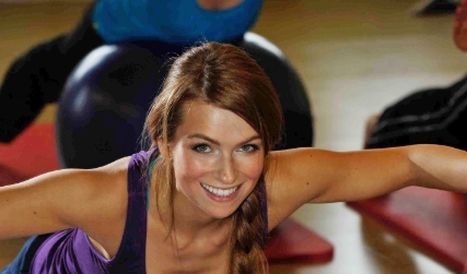 Sportlerin liegt bäuchlings auf eine Gymnastikball und schwingt den Oberkörper nach oben